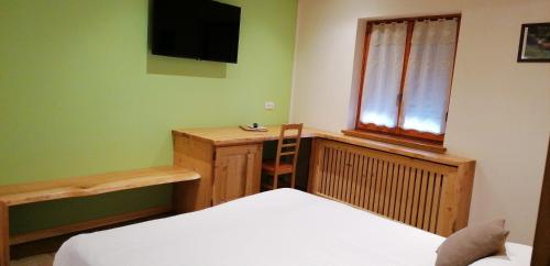 a bedroom with a bed and a desk and a television at Hotel La Baita in Malborghetto Valbruna