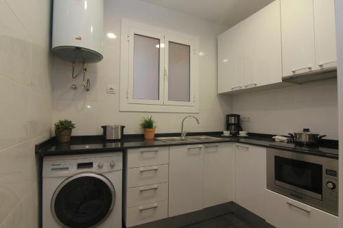 a white kitchen with a washing machine in it at FELIP II - Spacious and quiet apartments in Barcelona