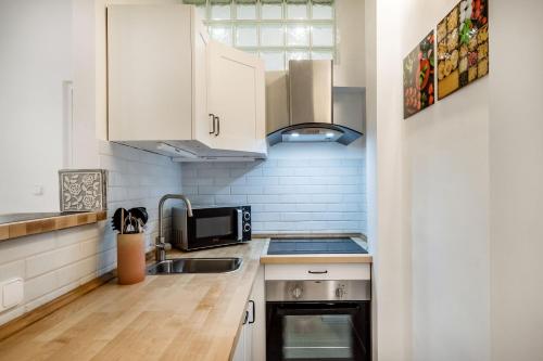 a kitchen with white cabinets and a sink and a microwave at Viktoria design studio apartment in Budapest