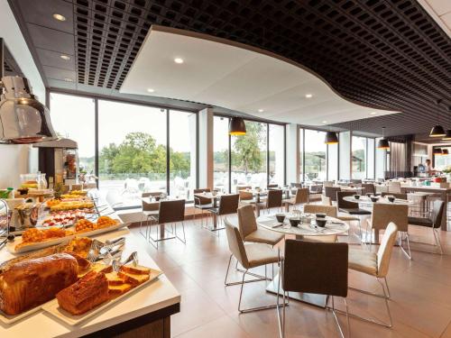 un restaurant avec des tables et des chaises et de la nourriture exposée dans l'établissement Novotel Limoges Le Lac, à Limoges