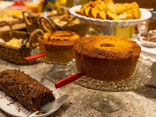a table with a cake on a plate and other desserts at ibis Styles Campina Grande in Campina Grande