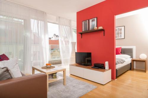 a living room with a red accent wall at Balcony Dream Mariahilf in Vienna