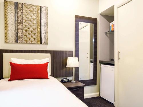 a bedroom with a red pillow on a bed at ibis Styles Kingsgate Hotel in Melbourne