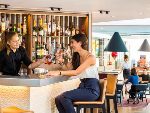 two women sitting at a bar drinking wine at Mercure Orange Centre A7/A9 in Orange