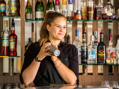 a woman sitting at a bar holding a camera at Mercure Orange Centre A7/A9 in Orange