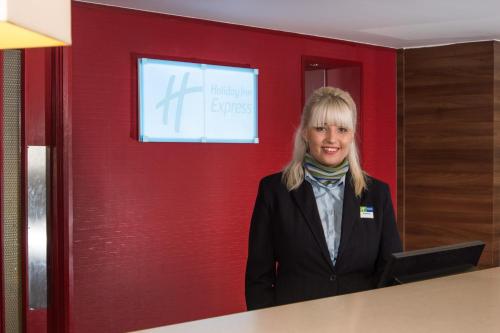 a woman standing in front of a red wall at Holiday Inn Express Stoke-On-Trent, an IHG Hotel in Stoke on Trent
