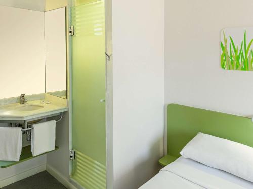 a bathroom with a bed and a sink and a mirror at ibis budget Sao Paulo Paraiso in Sao Paulo