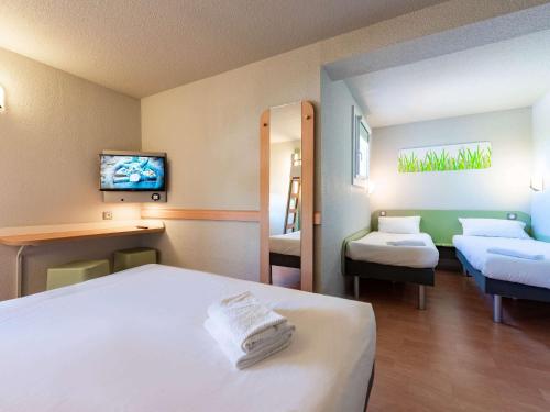 Cette chambre comprend 2 lits et une télévision. dans l'établissement Ibis Budget Avignon Nord, au Pontet