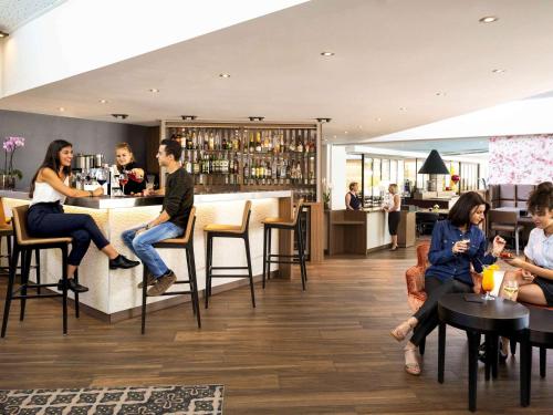 a group of people sitting at a bar in a restaurant at Mercure Orange Centre A7/A9 in Orange