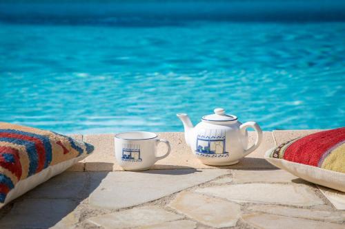 duas chávenas de chá e um bule sentado ao lado de uma piscina em La Tour de la Rose - Villa Bohemian em Valbonne