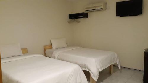 Cette chambre comprend 2 lits et une télévision murale. dans l'établissement Mjc New township 6BR by Natol Homestay-MJC, à Kuching