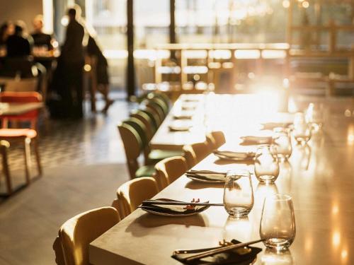 a row of tables in a restaurant with glasses at Ibis Styles Hobart in Hobart