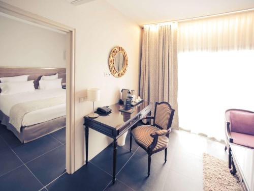 a hotel room with a desk and a bed and a mirror at Mercure Cayenne Royal Amazonia in Cayenne