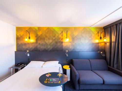 a hotel room with a bed and a couch at ibis Styles Poitiers Nord in Poitiers