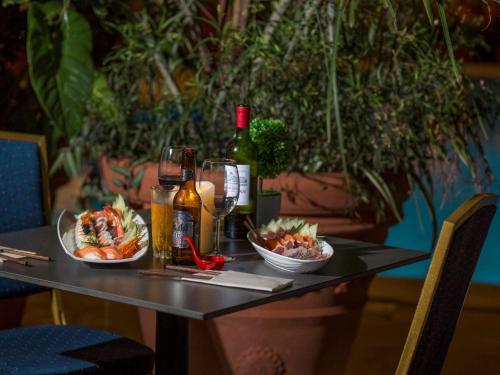 a table with two plates of food and a bottle of wine at Mercure Cayenne Royal Amazonia in Cayenne