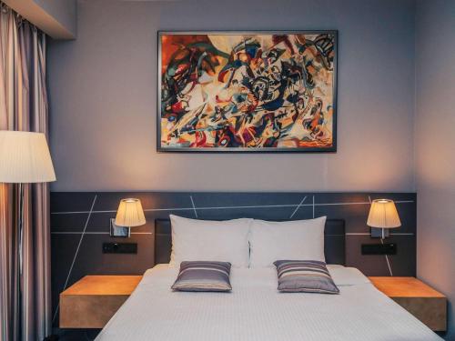 a bedroom with a bed with a painting above it at Mercure Kyiv Congress in Kyiv