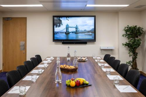 a conference room with a long table with a tv on the wall at St Giles London – A St Giles Hotel in London