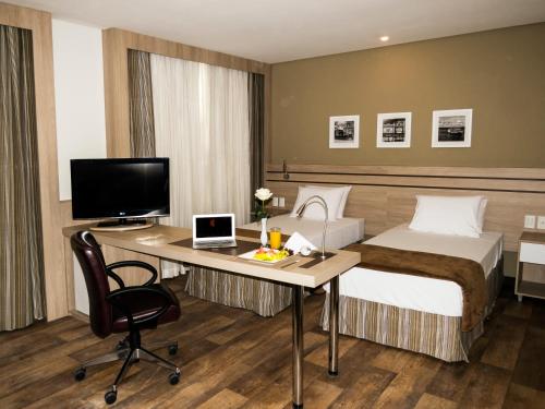 a hotel room with a bed and a desk with a computer at Intercity Manaus in Manaus