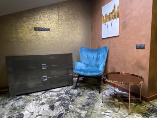 a blue chair and a table in a room at ArtApart Vozdvigenka in Kyiv