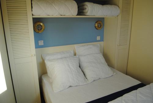 Cette chambre comprend un lit avec des oreillers blancs. dans l'établissement T2 les pieds dans l'eau, mer et piscine, à Lacanau-Océan