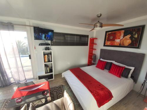 1 dormitorio con 1 cama grande con almohadas rojas en Atlantic Studio - Compact unit with Sea Views en Melkbosstrand