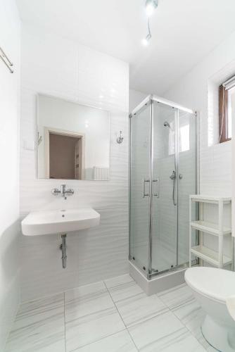 a white bathroom with a sink and a shower at Villa Azalia in Jastrzębia Góra
