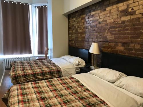 two beds in a room with a brick wall at Hotel La Residence du Voyageur in Montréal