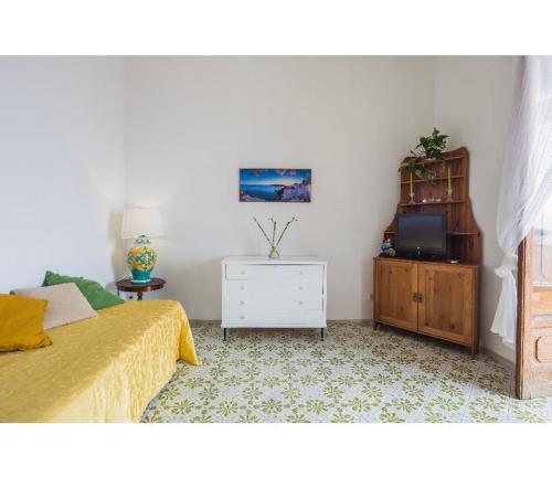um quarto com uma cama, uma cómoda e uma televisão em Casa Marty em Positano