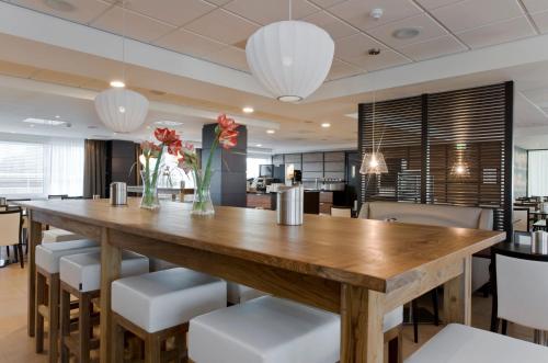 a dining room with a large wooden table and chairs at Holiday Inn Express Amsterdam - Sloterdijk Station by IHG in Amsterdam