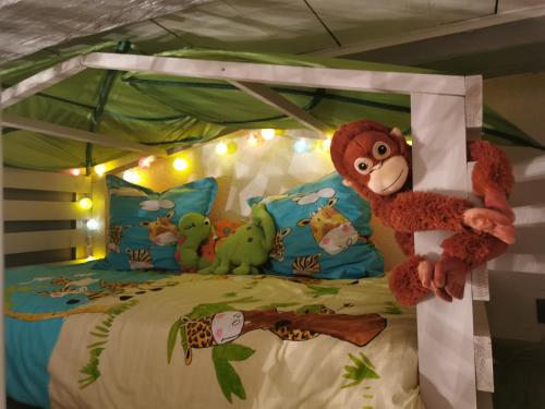 a stuffed monkey is sitting on a bed at Le gite de Coco in Riquewihr