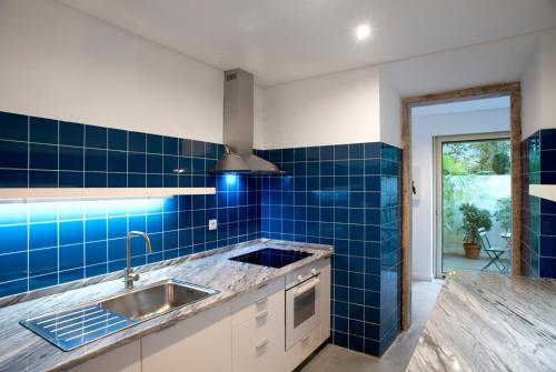 a kitchen with a sink and blue tiles on the wall at Art Gallery Apartment in Lisbon