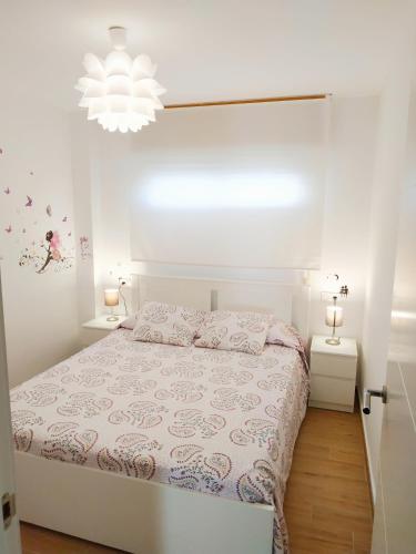 a white bedroom with a bed and a chandelier at Apartamento Cruise Views in Almuñécar