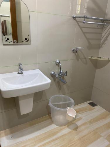 a bathroom with a sink and a trash can at Villa Anandha in Trivandrum