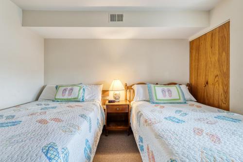 a bedroom with two beds and a night stand with a lamp at Jamaica Place 107 in Ocean City