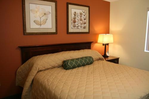 ein Schlafzimmer mit einem Bett und zwei Bildern an der Wand in der Unterkunft Affordable Suites - Fayetteville/Fort Bragg in Fayetteville