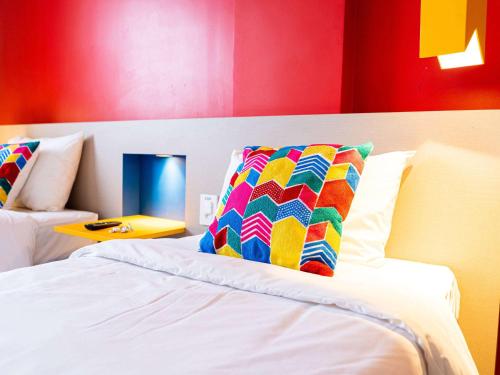 a bedroom with a bed with a colorful pillow on it at ibis Styles Campina Grande in Campina Grande
