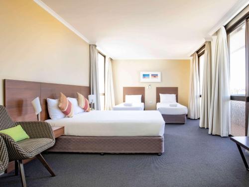 a hotel room with two beds and two chairs at ibis Styles Mt Isa Verona in Mount Isa