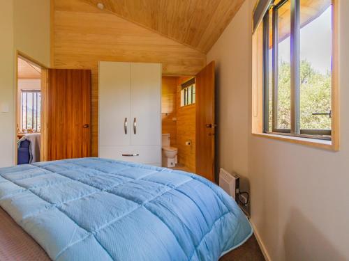 a bedroom with a blue bed and a window at The Snowglobe - Ohakune Modern Yurt Style Chalet in Ohakune