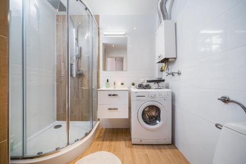 a bathroom with a washing machine and a shower at Sunshine Parkside Hideaway - 3 Bedroom in Kraków