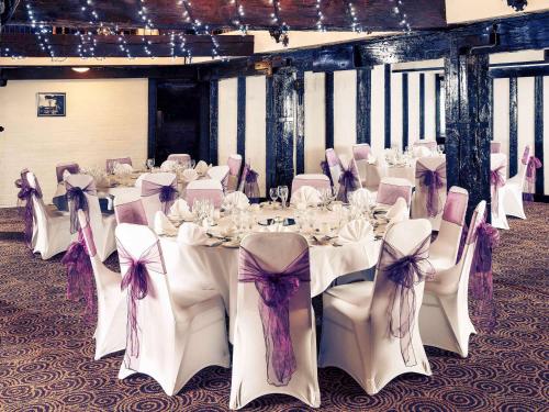 a banquet hall with white tables and chairs with bows at Mercure Perth Hotel in Perth