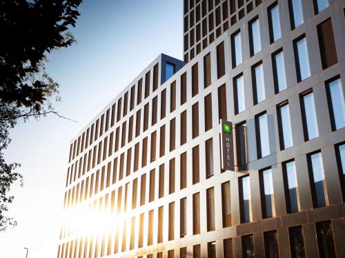 a tall building with the sun shining behind it at ibis Styles Basel City in Basel