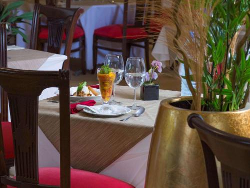 a table with two wine glasses and a plate of food at Mercure Cayenne Royal Amazonia in Cayenne