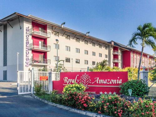 Um edifício com uma cerca rosa à frente. em Mercure Cayenne Royal Amazonia em Caiena