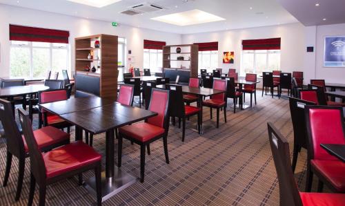 a dining room with tables and red chairs at Holiday Inn Express Stoke-On-Trent by IHG in Stoke on Trent
