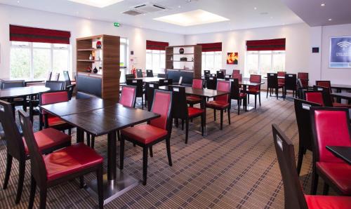 a dining room with tables and red chairs at Holiday Inn Express Stoke-On-Trent, an IHG Hotel in Stoke on Trent