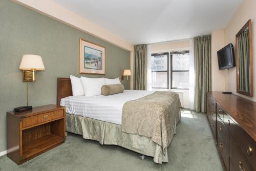 um quarto de hotel com uma cama e uma televisão em Murray Hill East Suites em Nova York