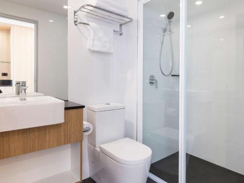 a white bathroom with a toilet and a shower at Ibis Styles Hobart in Hobart