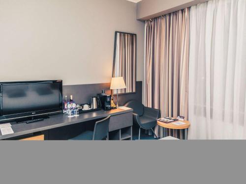 a hotel room with a television and a desk with chairs at Mercure Kyiv Congress in Kyiv
