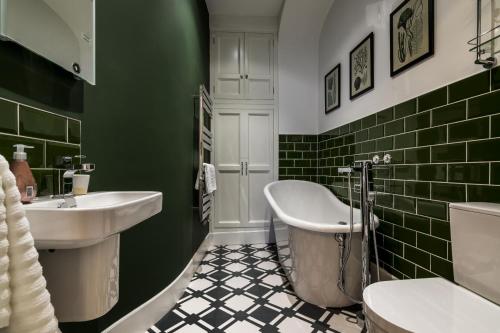a green bathroom with a tub and a sink at Fisherman's Catch - Two Bedroom Luxury Apartment - Tenby in Tenby