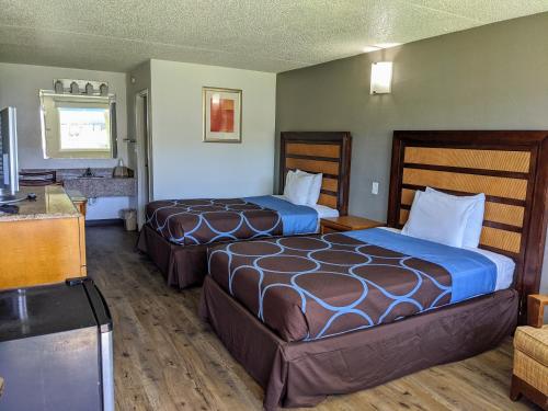 a hotel room with two beds and a television at Garden Inn & Suites in Pensacola